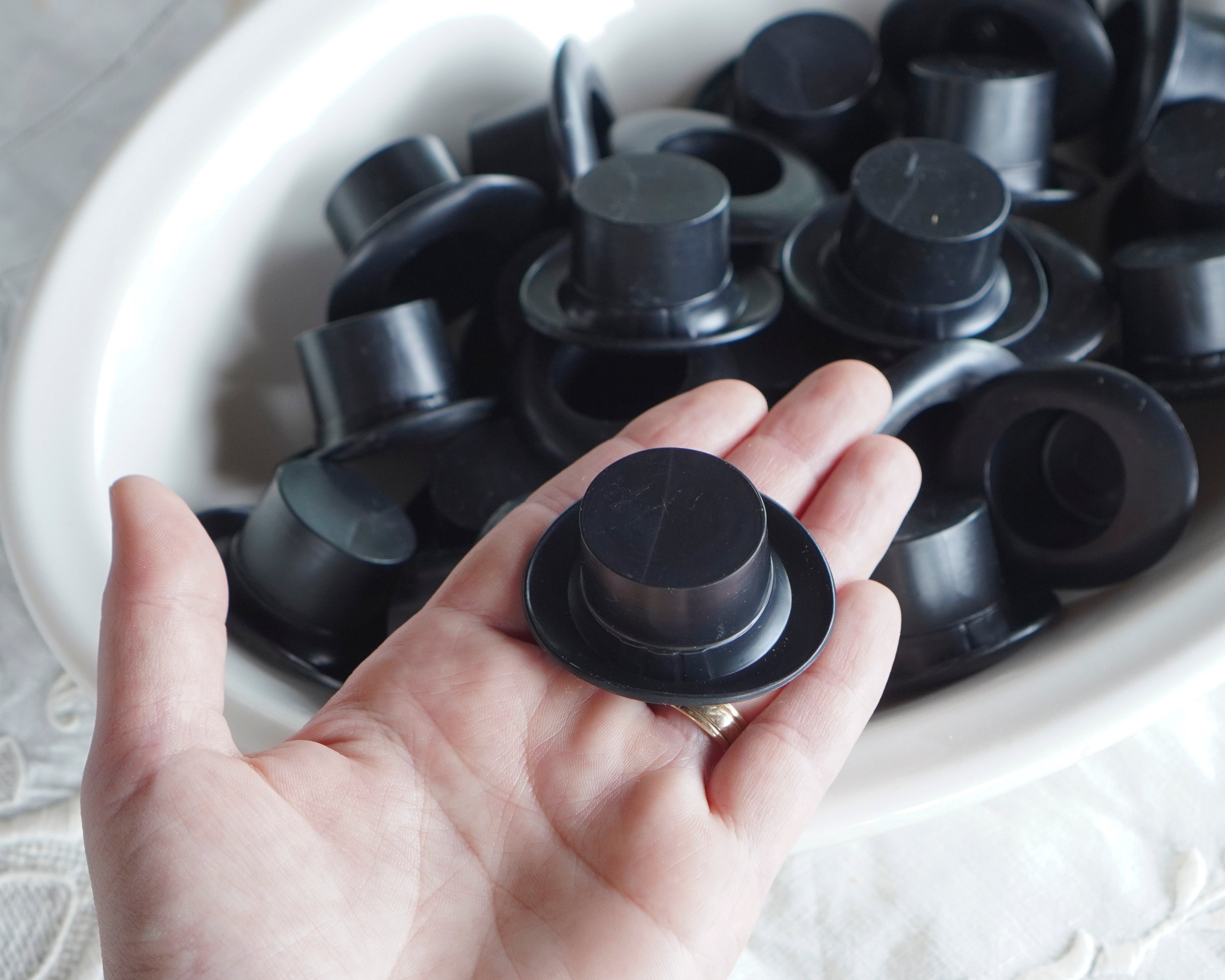 Hand holding a black plastic top hat with more in the background.