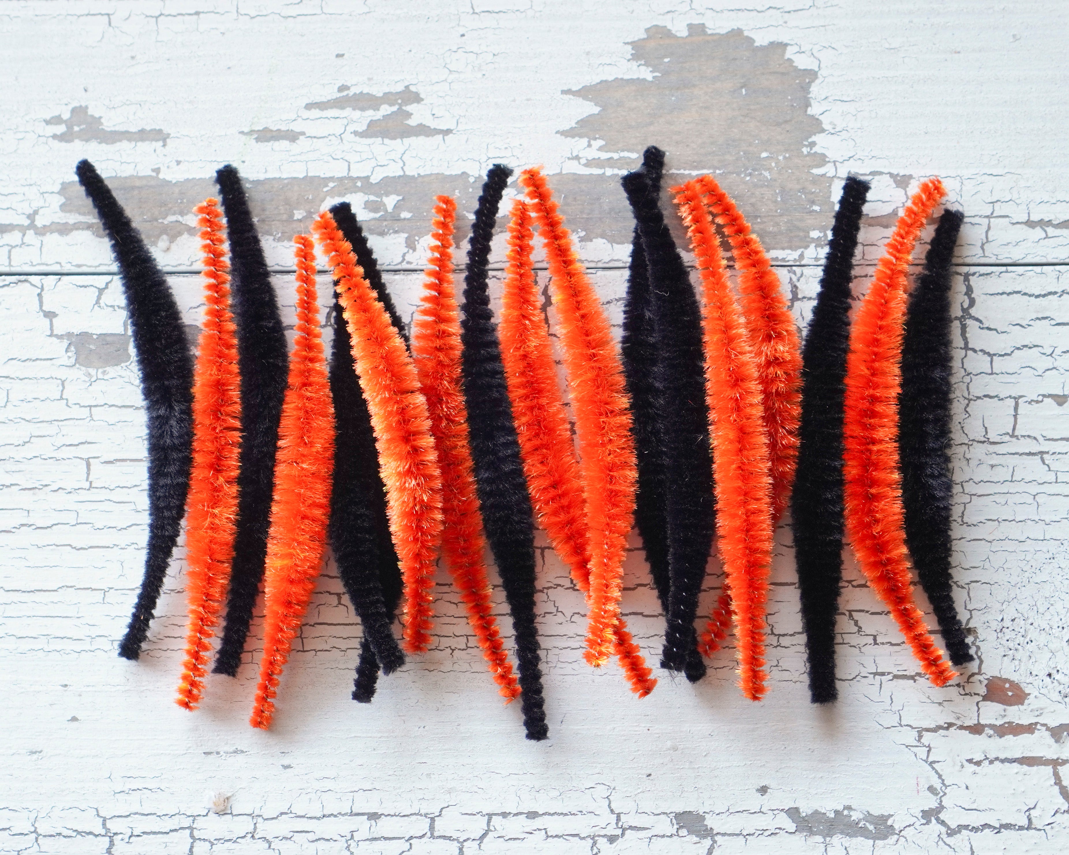 Orange and black halloween bump chenille pieces on a white wooden background.