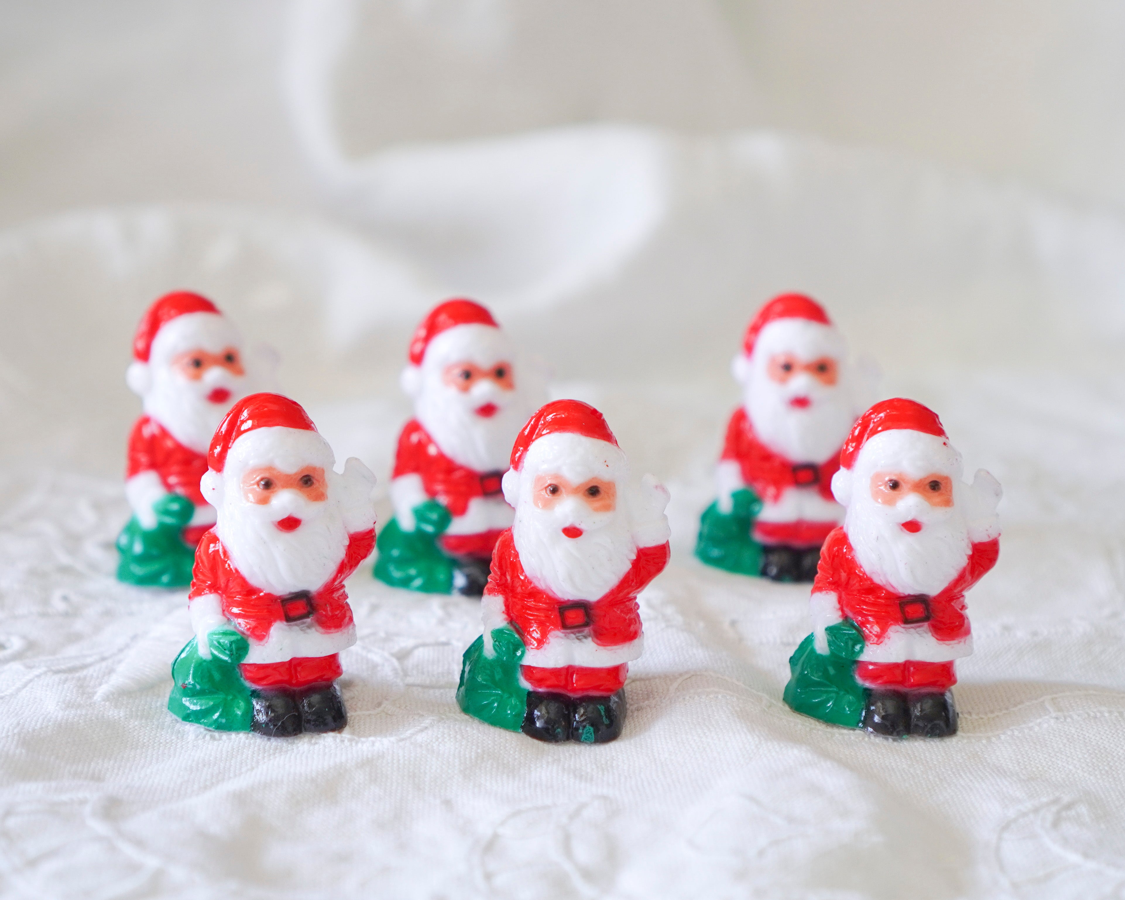 Set of miniature Santa Claus figurines on a textured white surface