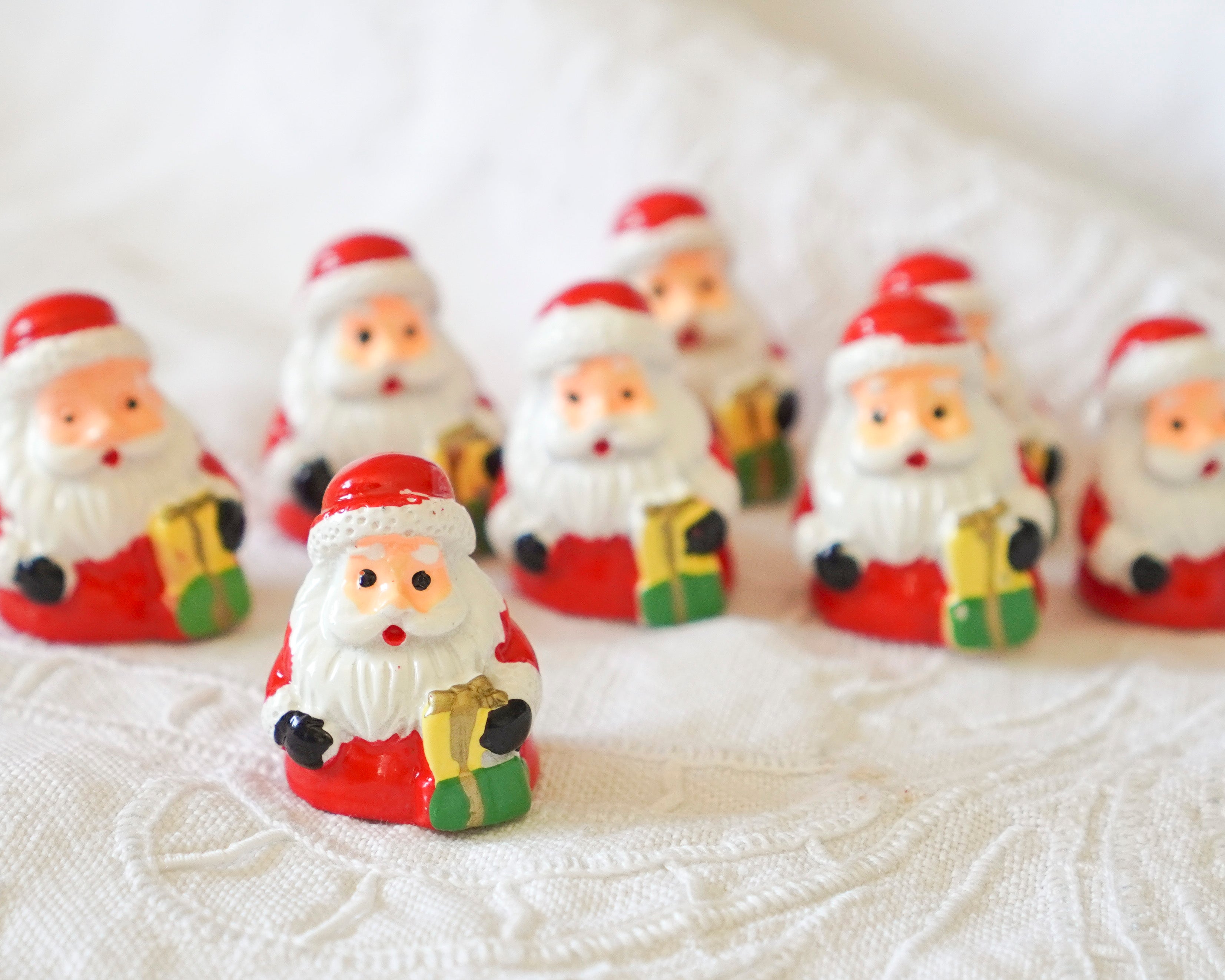 Small Santa Claus figurines on a textured white surface