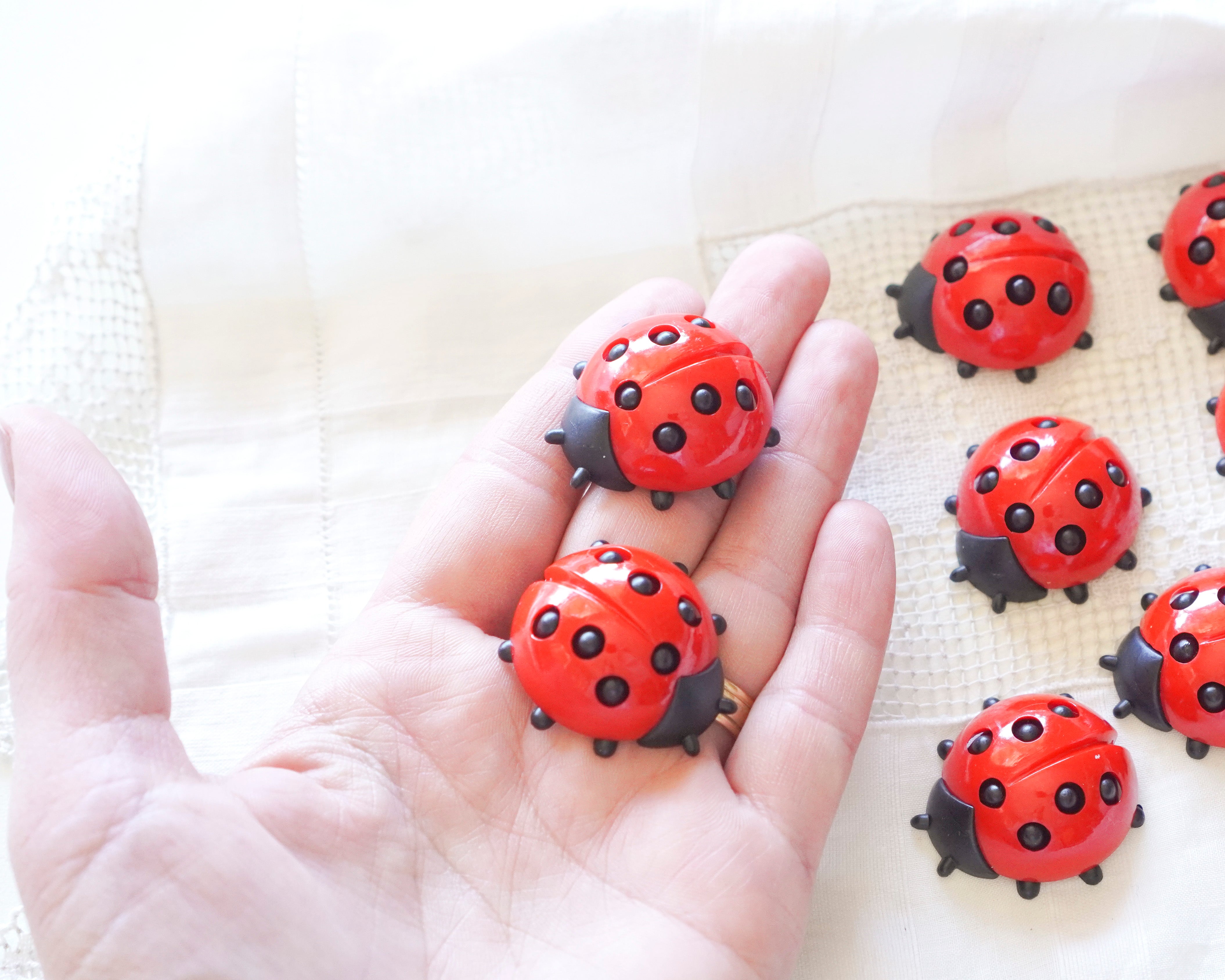 Red craft ladybugs on a hand and a white surface