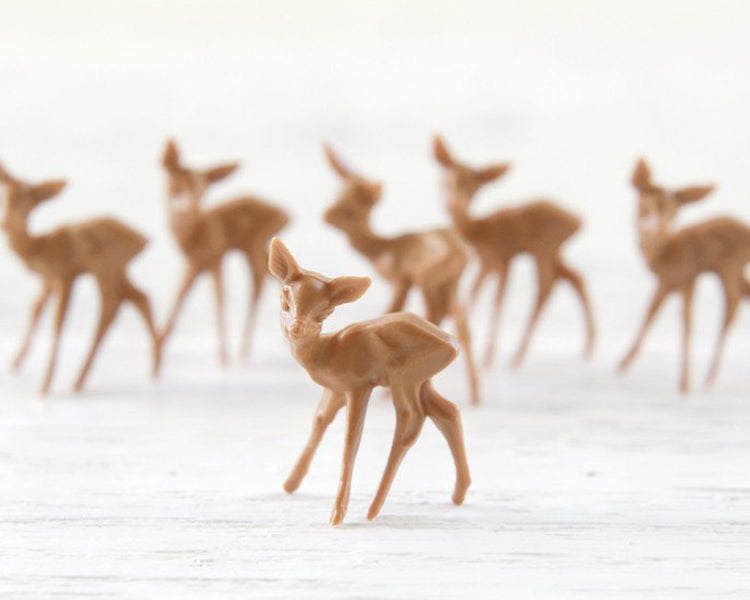 Miniature plastic deer for crafts arranged on a white background.