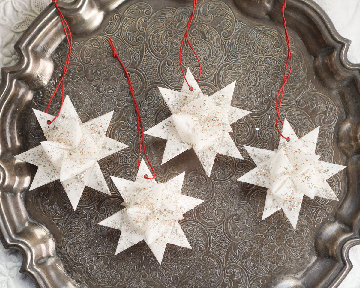 Four white star ornaments displayed on a silver plate.