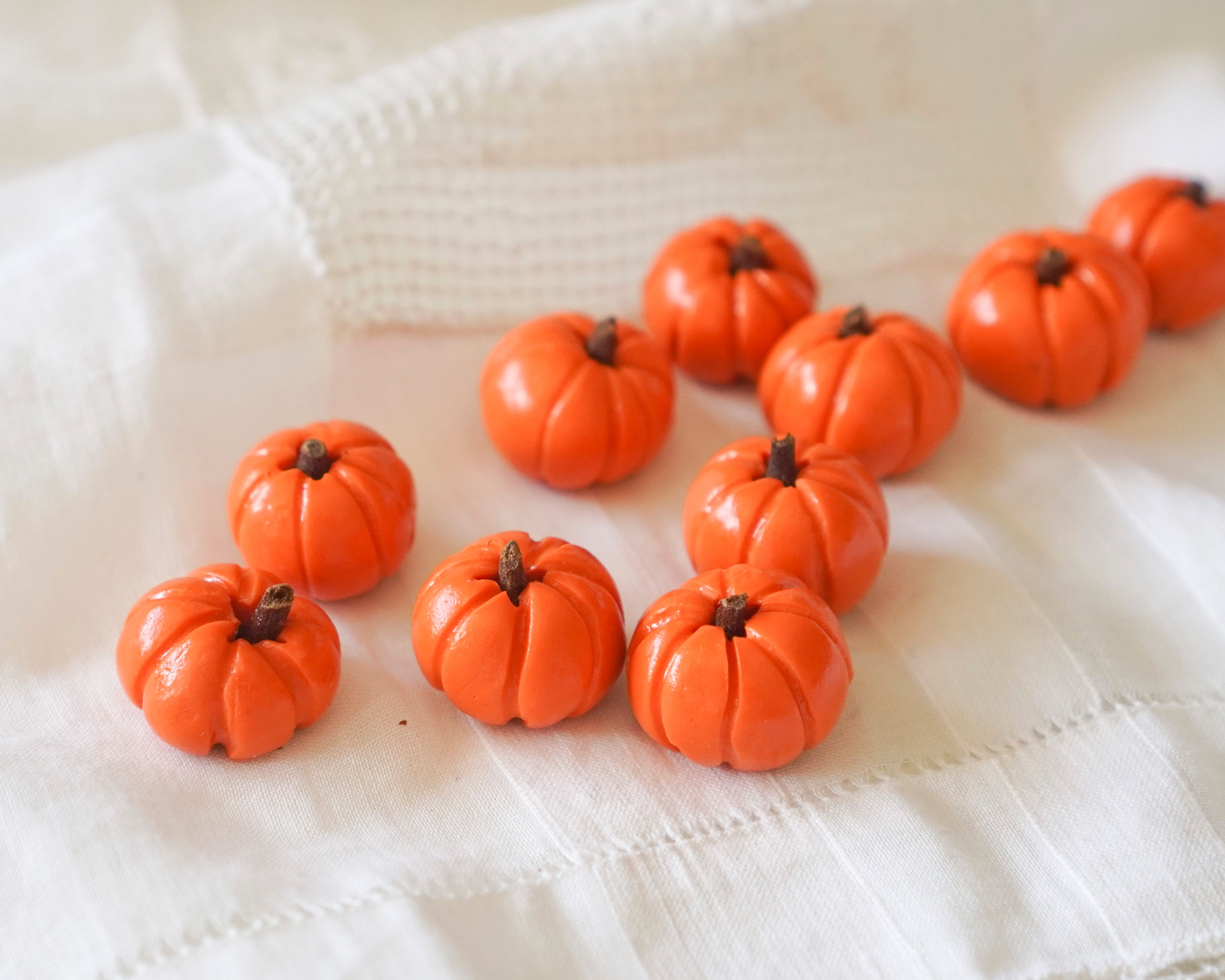 Small orange pumpkins on a white textured fabric background