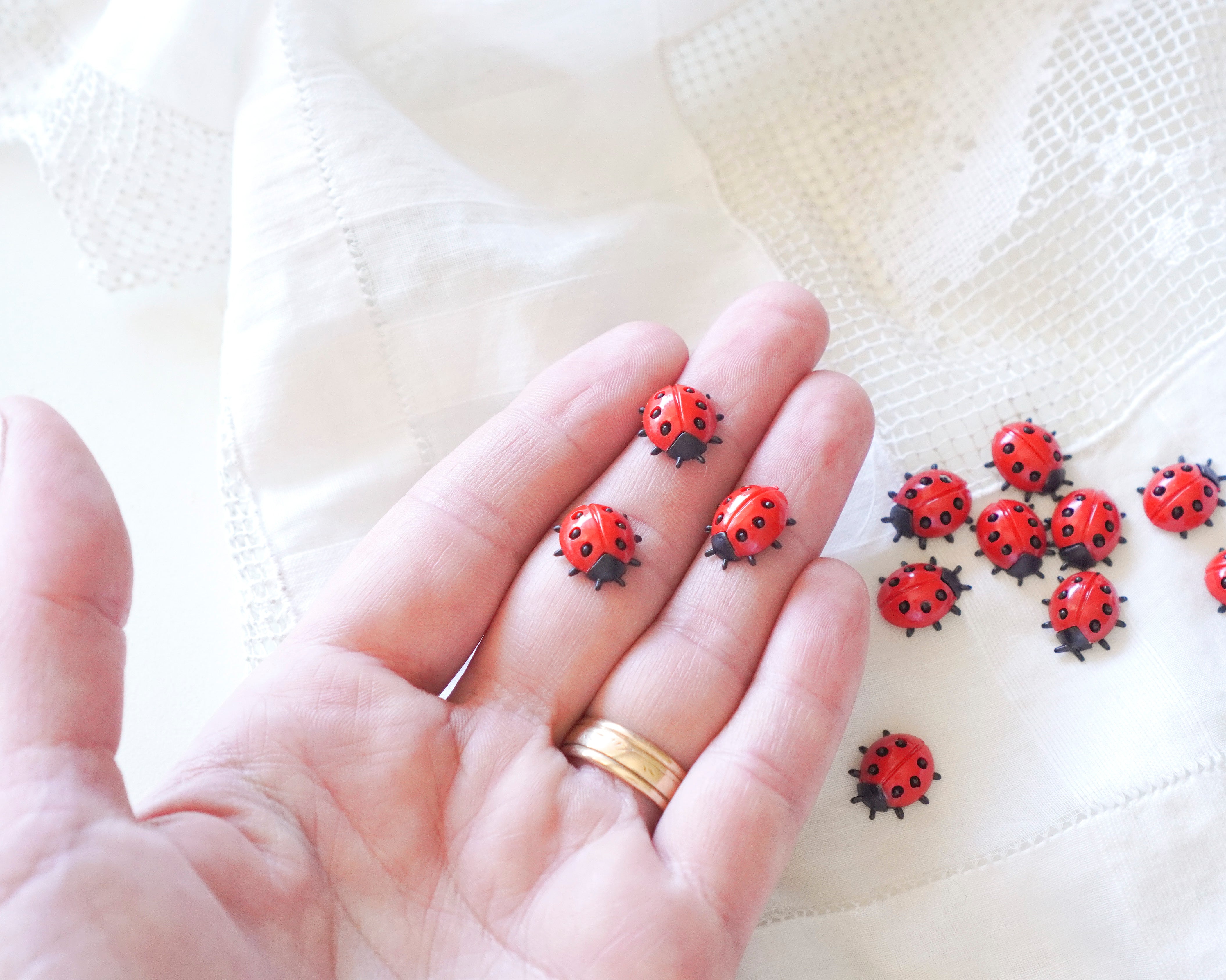 Hand with ladybug embellishments on a white fabric background