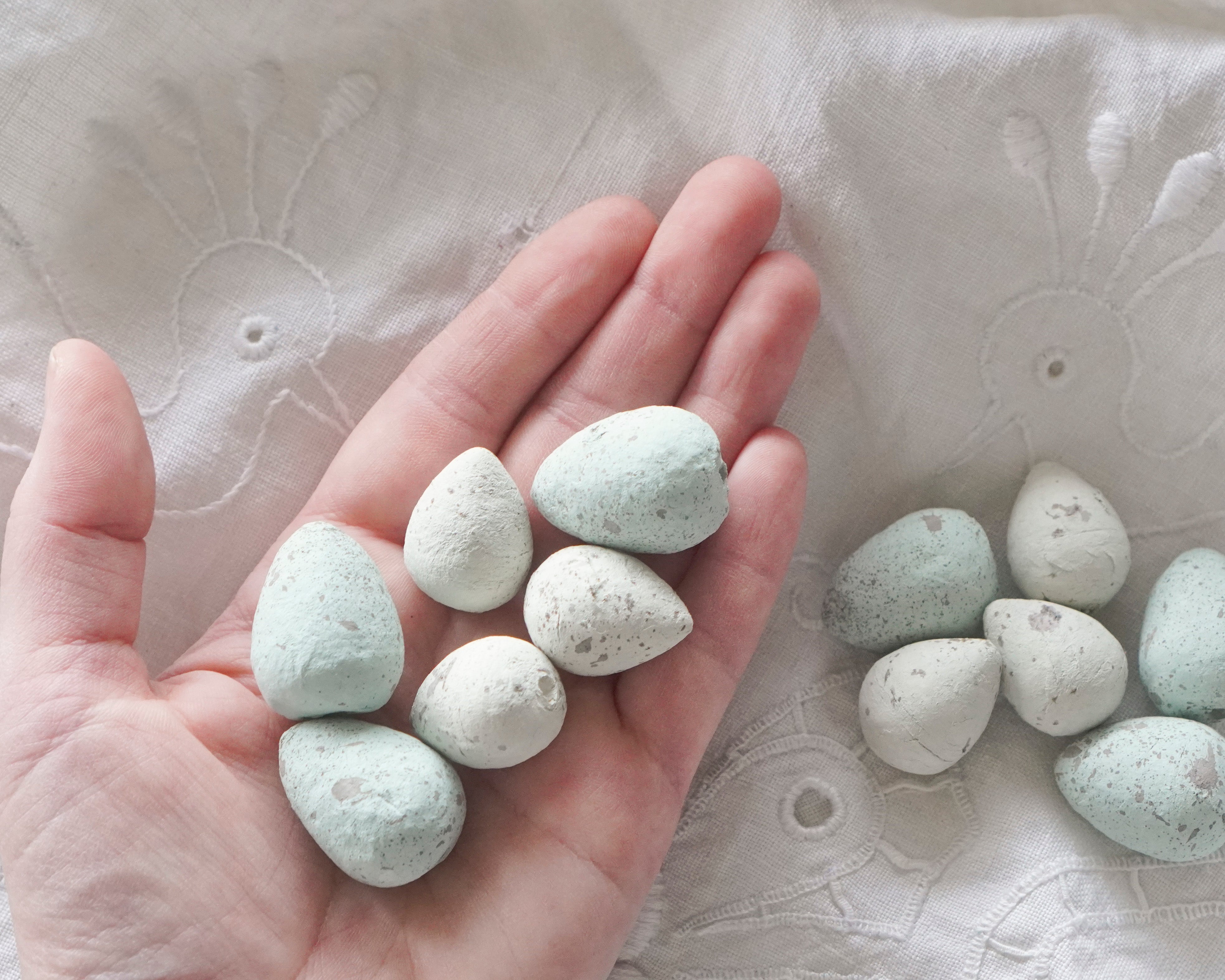 Hand holding blue easter eggs on a textured fabric background