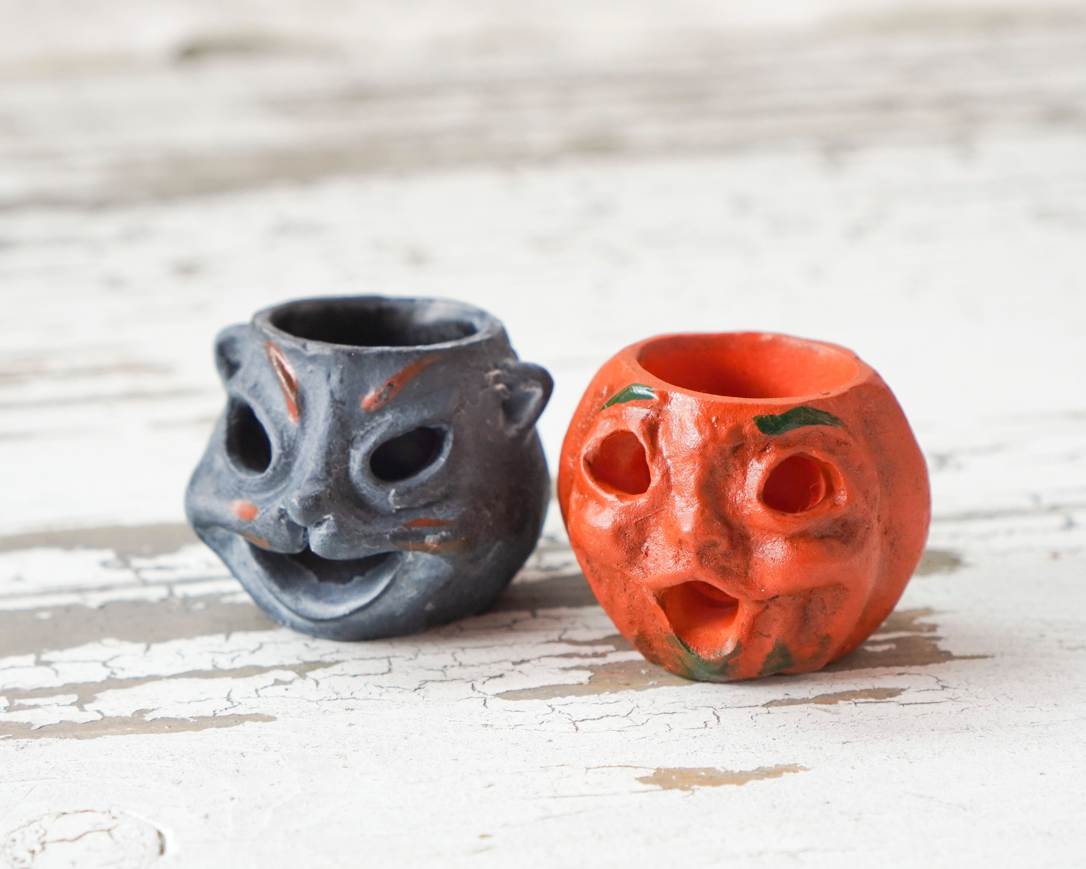 Two halloween mniatures, one black and one orange, on a wooden surface.