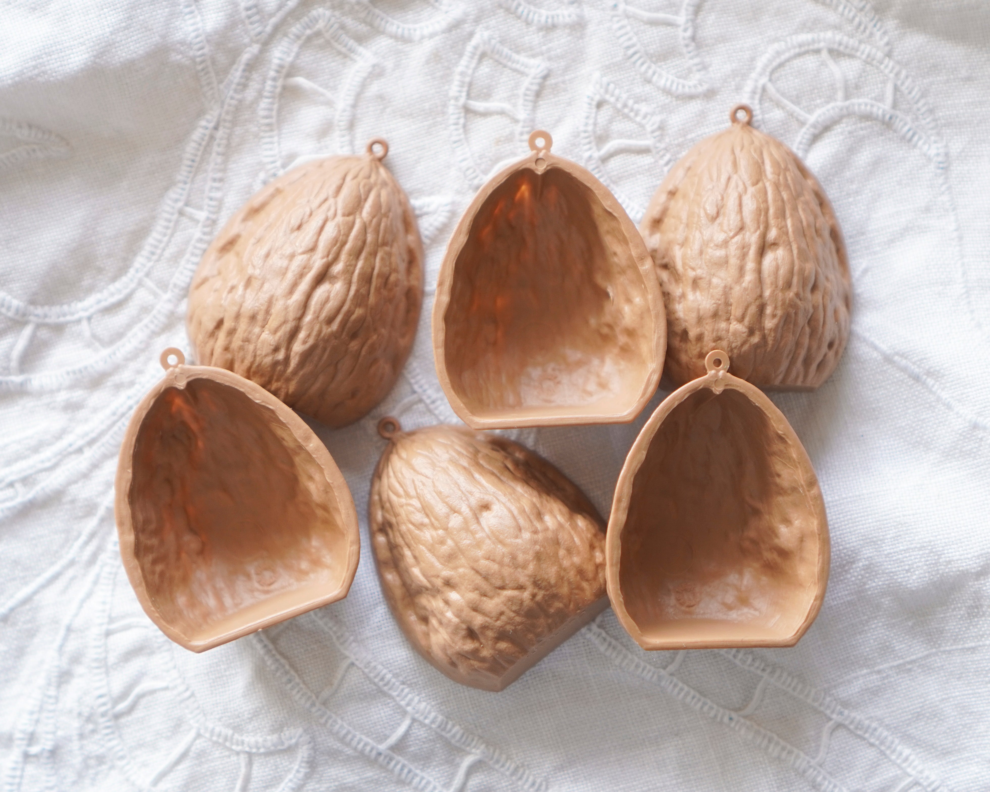 Set of six German plastic walnut shell-shaped ornaments on a textured white surface
