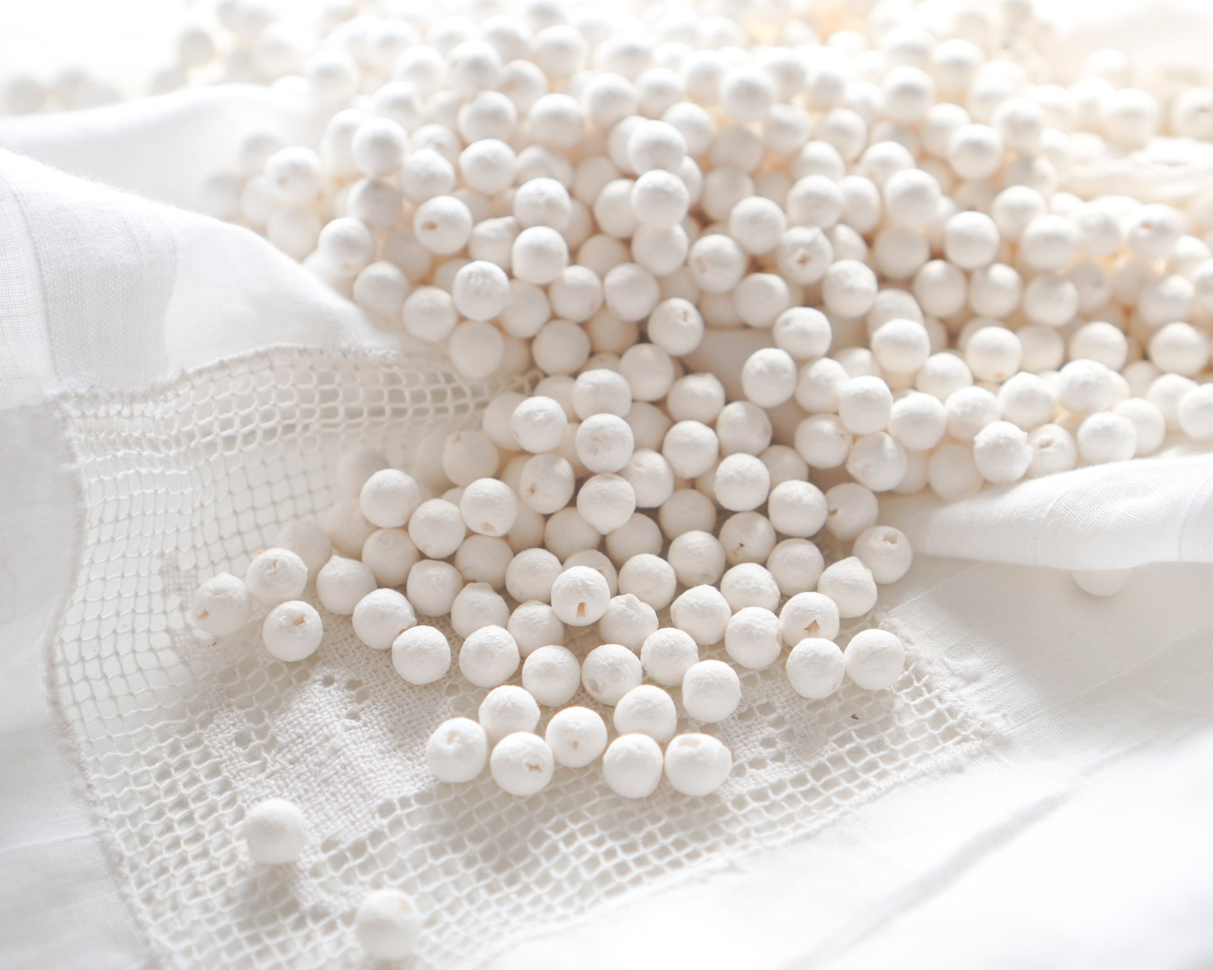 White spherical spun cotton balls on a white fabric background
