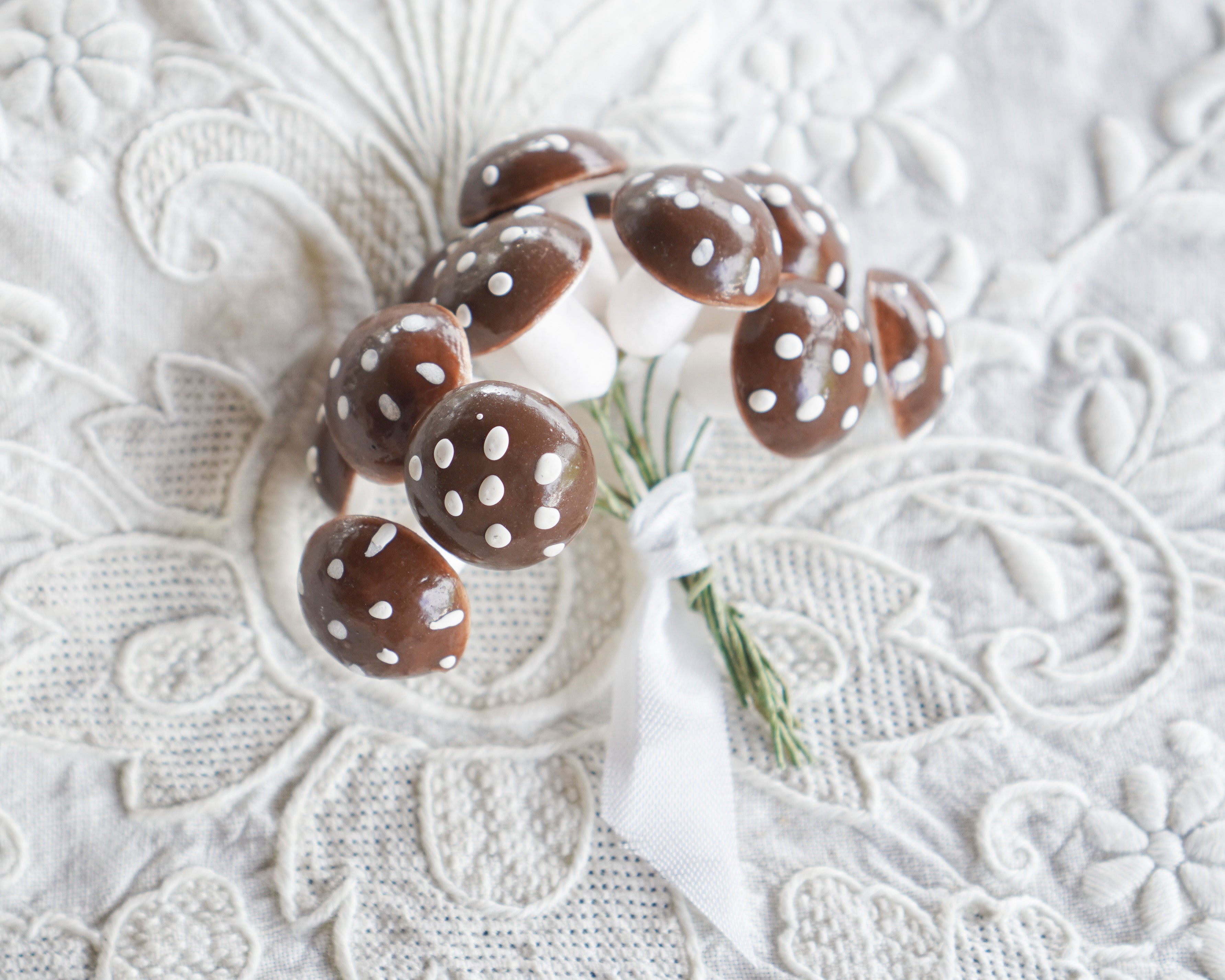 Brown spun cotton mushrooms with white spots on a textured white surface