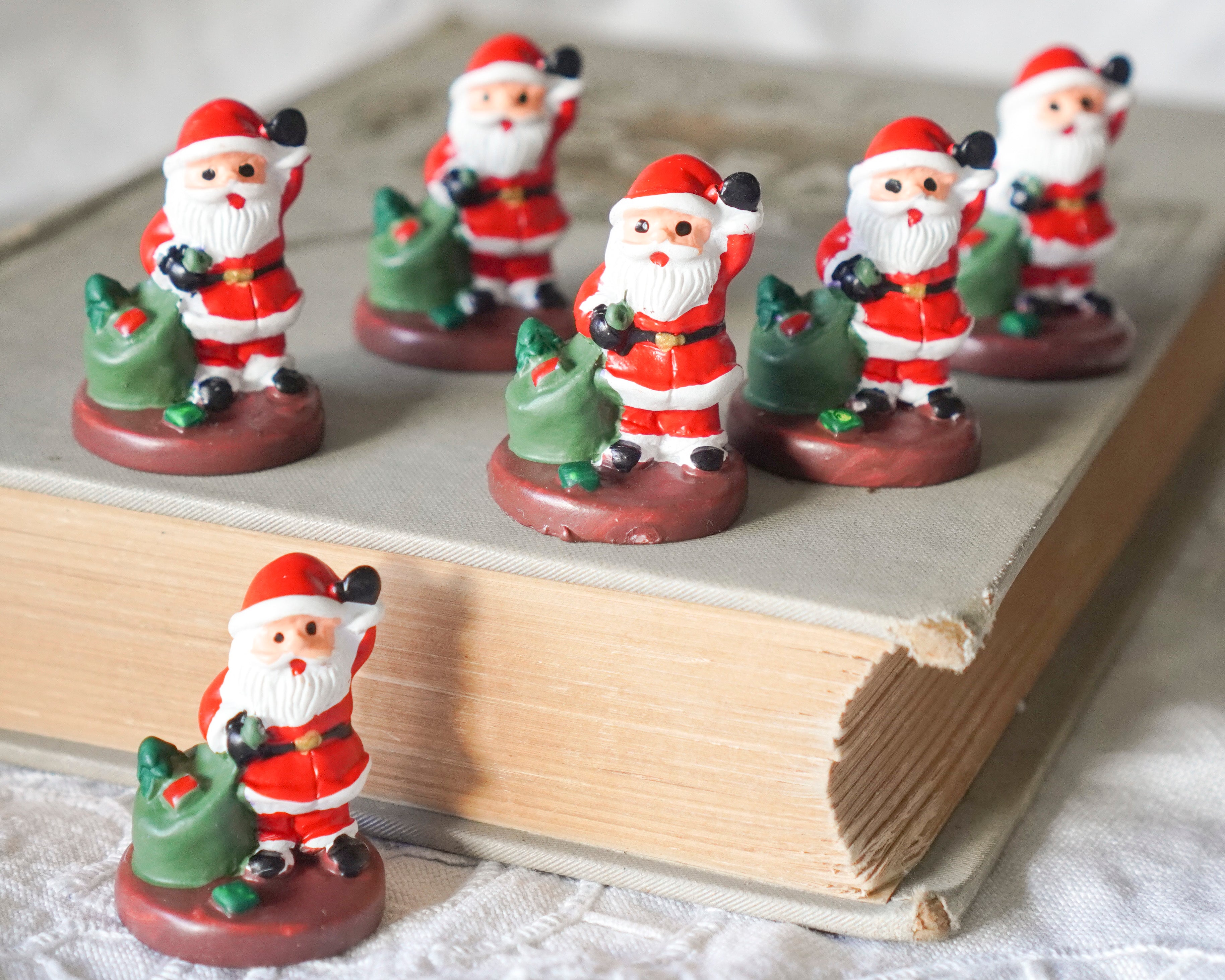 Miniature Santa Craft Figurines grouped on the cover of a book.