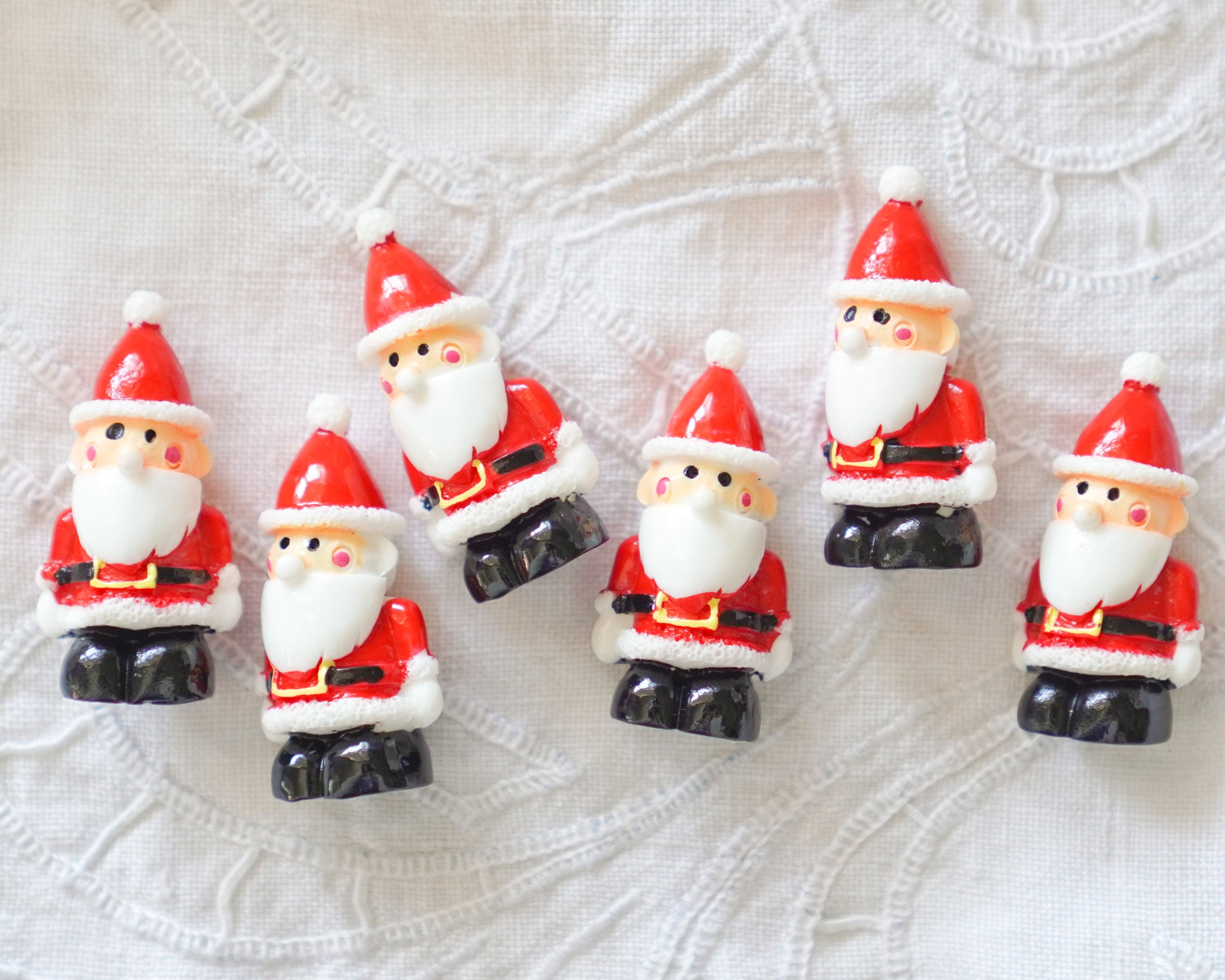 Set of miniature Santa Claus figurines on a textured white background