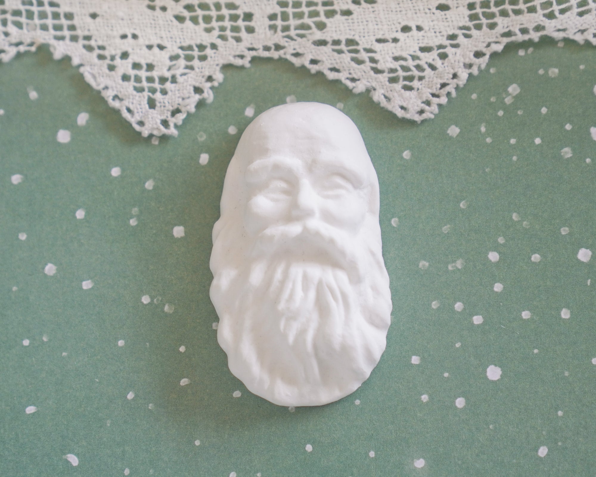 An old fashioned Santa doll face on a green background.