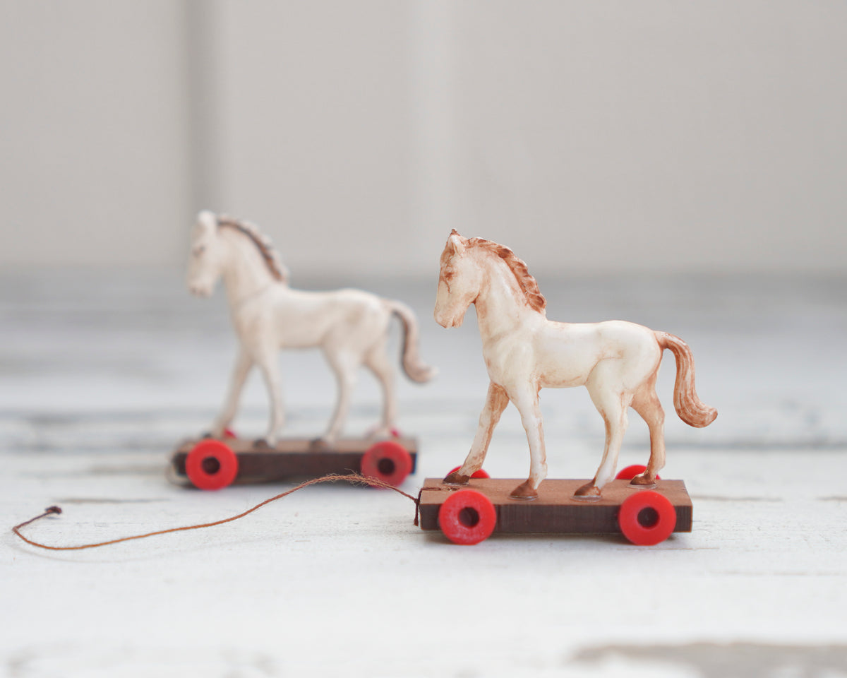 Miniature 1:12 antique pull toy horse models on a white wooden background.