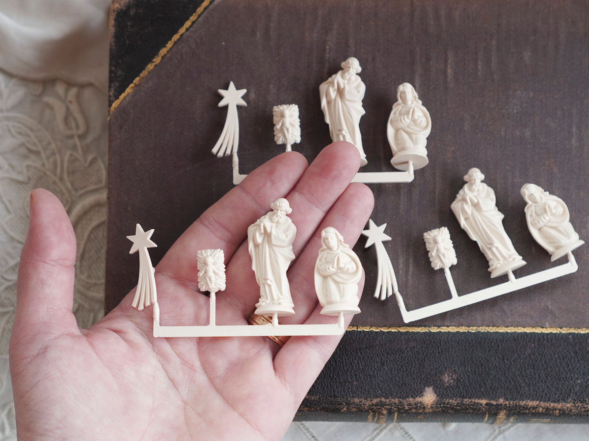 A hand holds a set of miniature plastic nativity figures