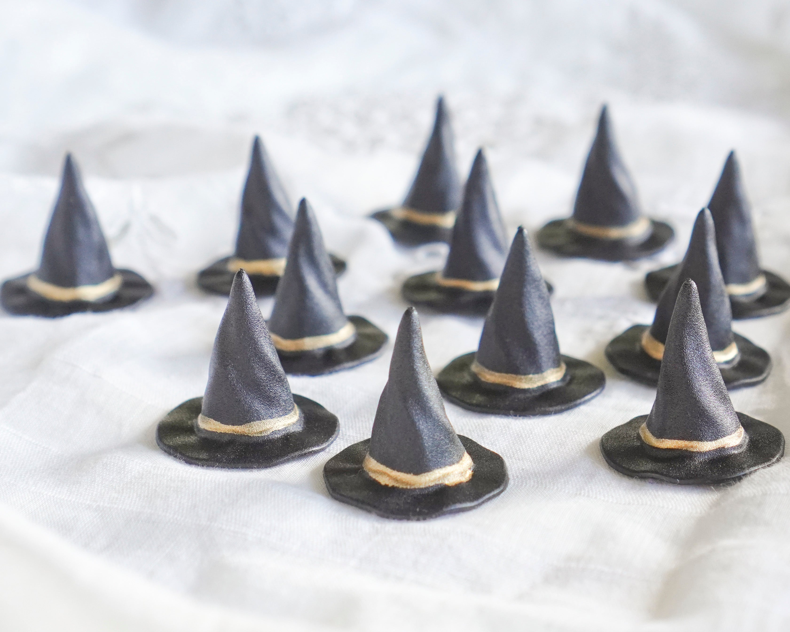 Small witch hats with gold accents on a white surface