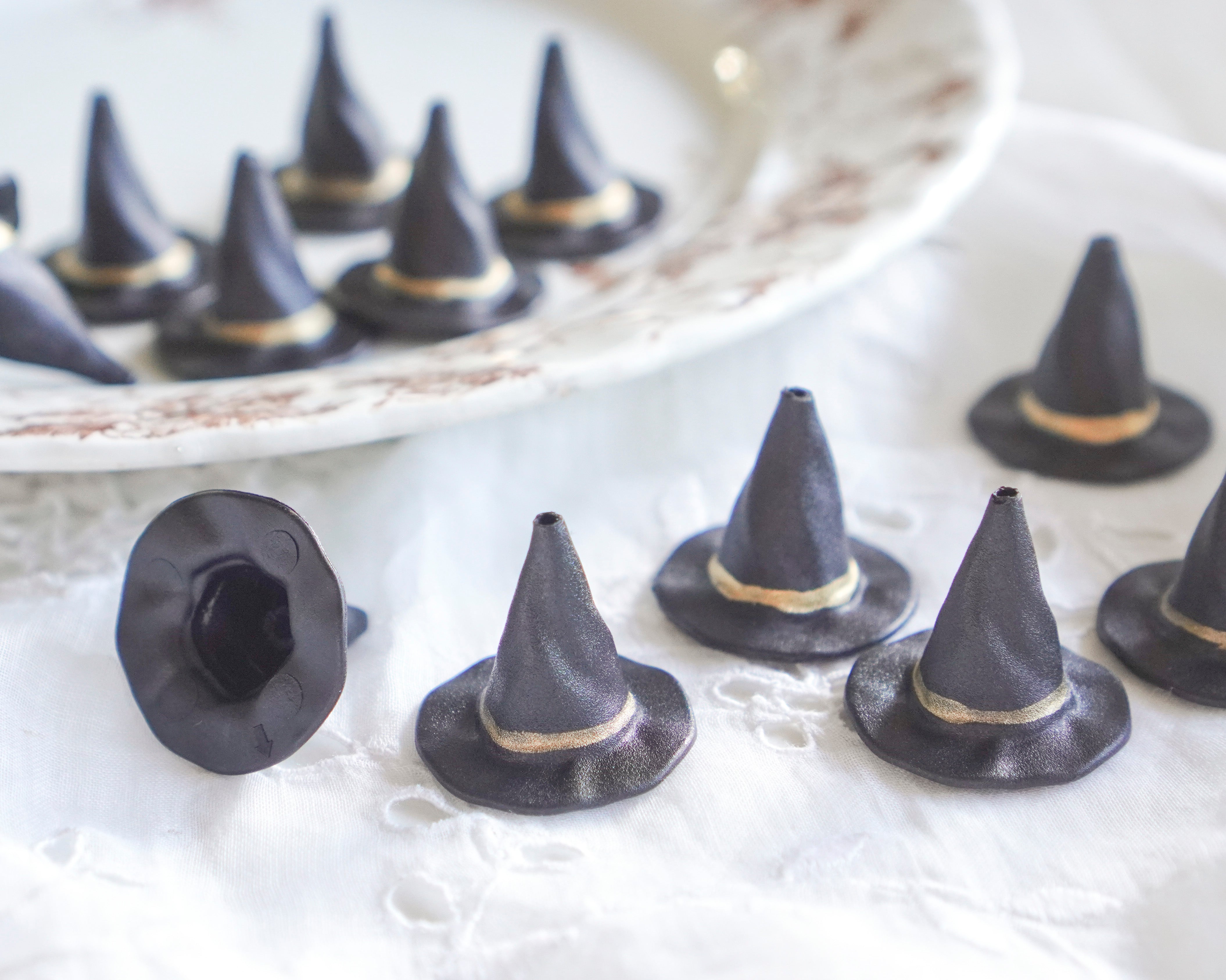 Black witch hats with gold accents on a white surface