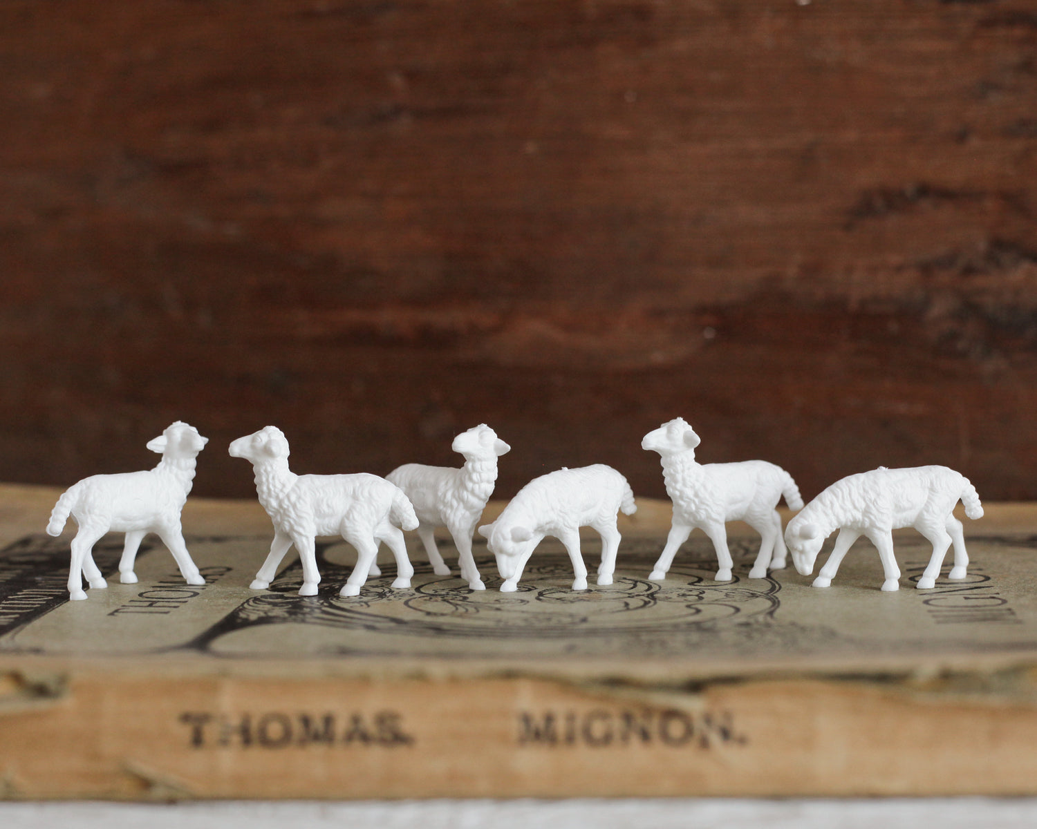Miniature sheep craft figurines sitting on a book.